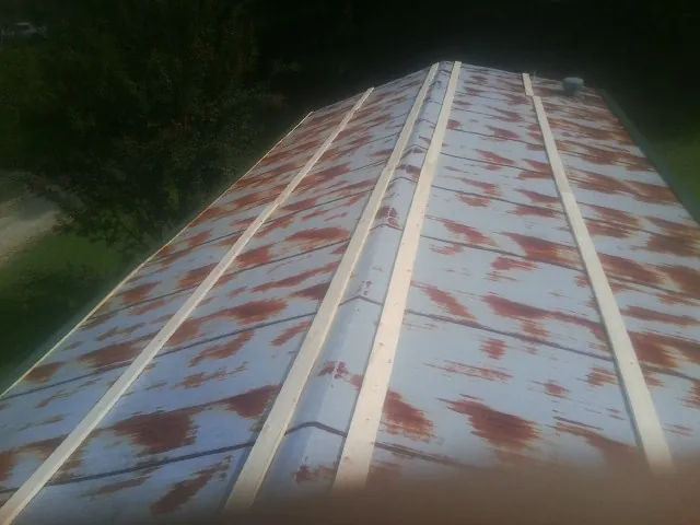 Rusted metal roof panels with new wood purlins before replacement — Storm Damage Roof Repair in Howard by Roofing Brothers