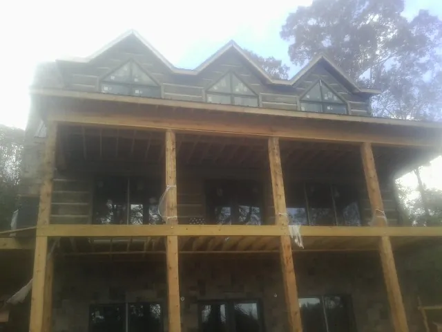 Dormers and porch framing on a large log home under construction — Roof Coating work by our crew in Howard